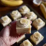 Delicious banana pudding bars topped with fresh banana slices and whipped cream.